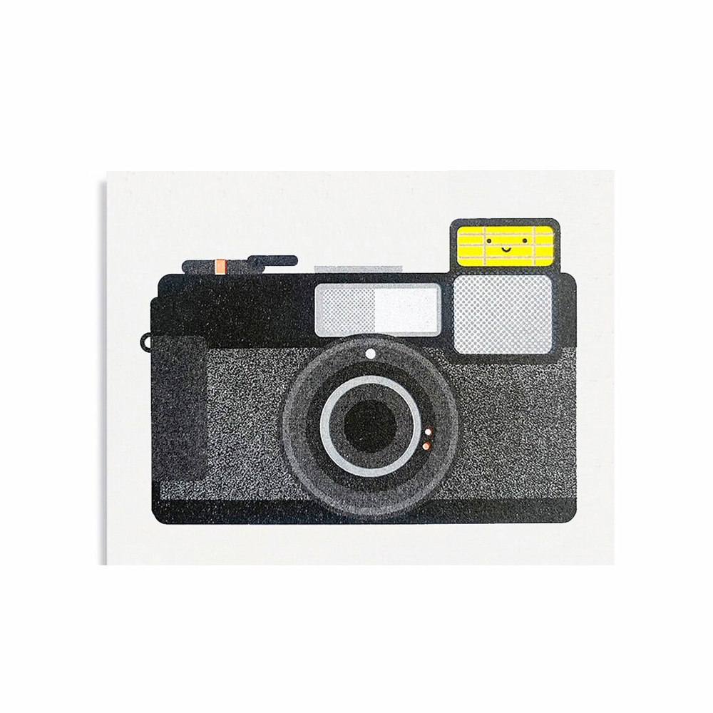 simple camera image of a point and shoot style camera in black and gray tones and flash has area is yellow with two eyes and simple smile made from a line to make a face