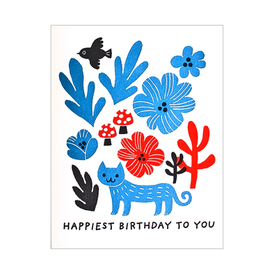Letterpressed blue cat with blue and red flowers and mushrooms and a black bird over the text HAPPIEST BIRTHDAY TO YOU