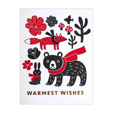 brown and red card with scarf-wearing fox, bunny, and bear surrounded by flowers and a couple mushrooms and a bird over the text WARMEST WISHES