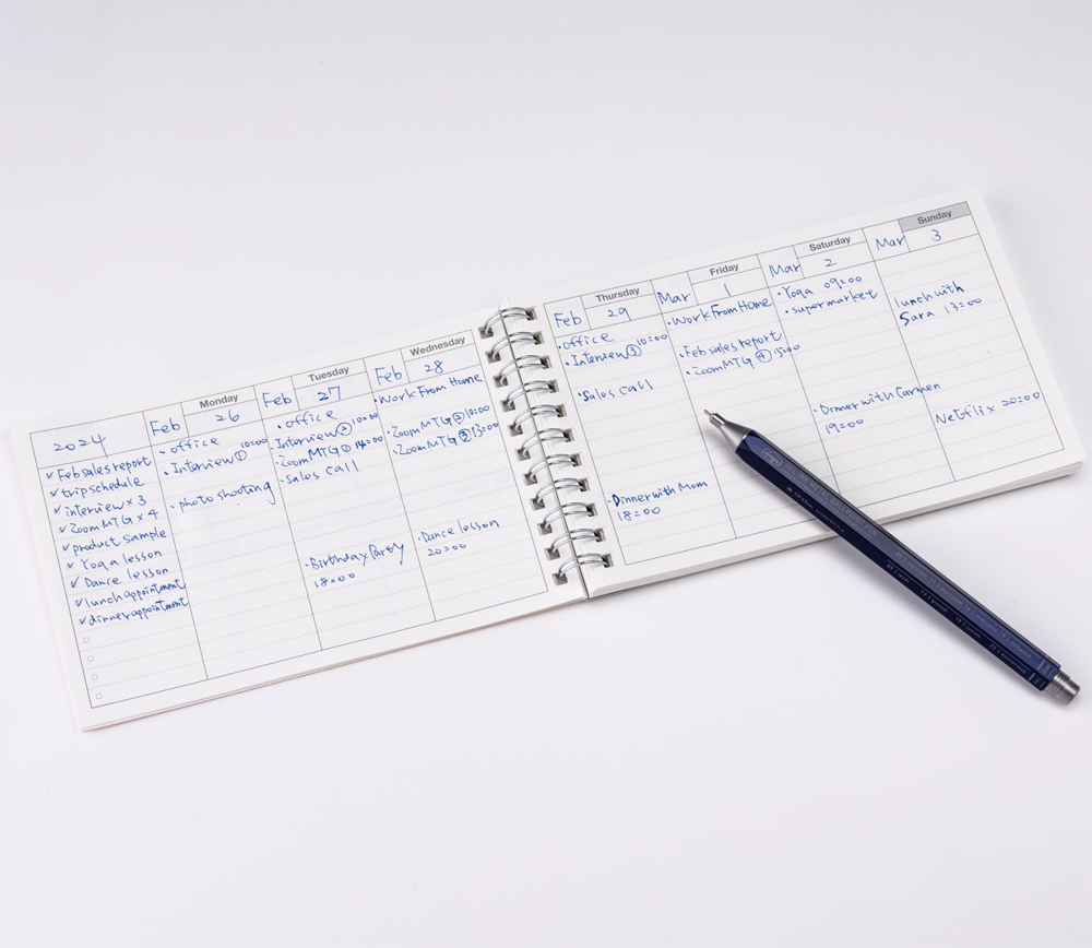 planner open with an example of how to fill it in and a pen for size reference.