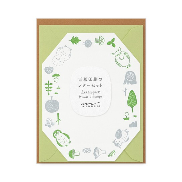 Octogon shaped paper with a green and gray border of owls, mushrooms, and trees and a green envelope.