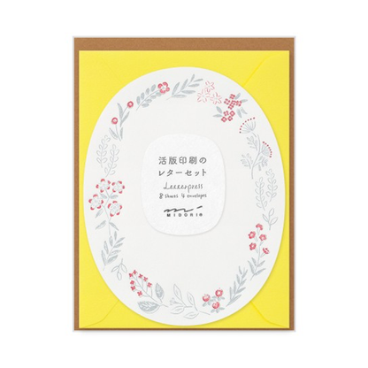 Oval sheet with 2-color border of gray and red flowers and leaves with a yellow envelope.